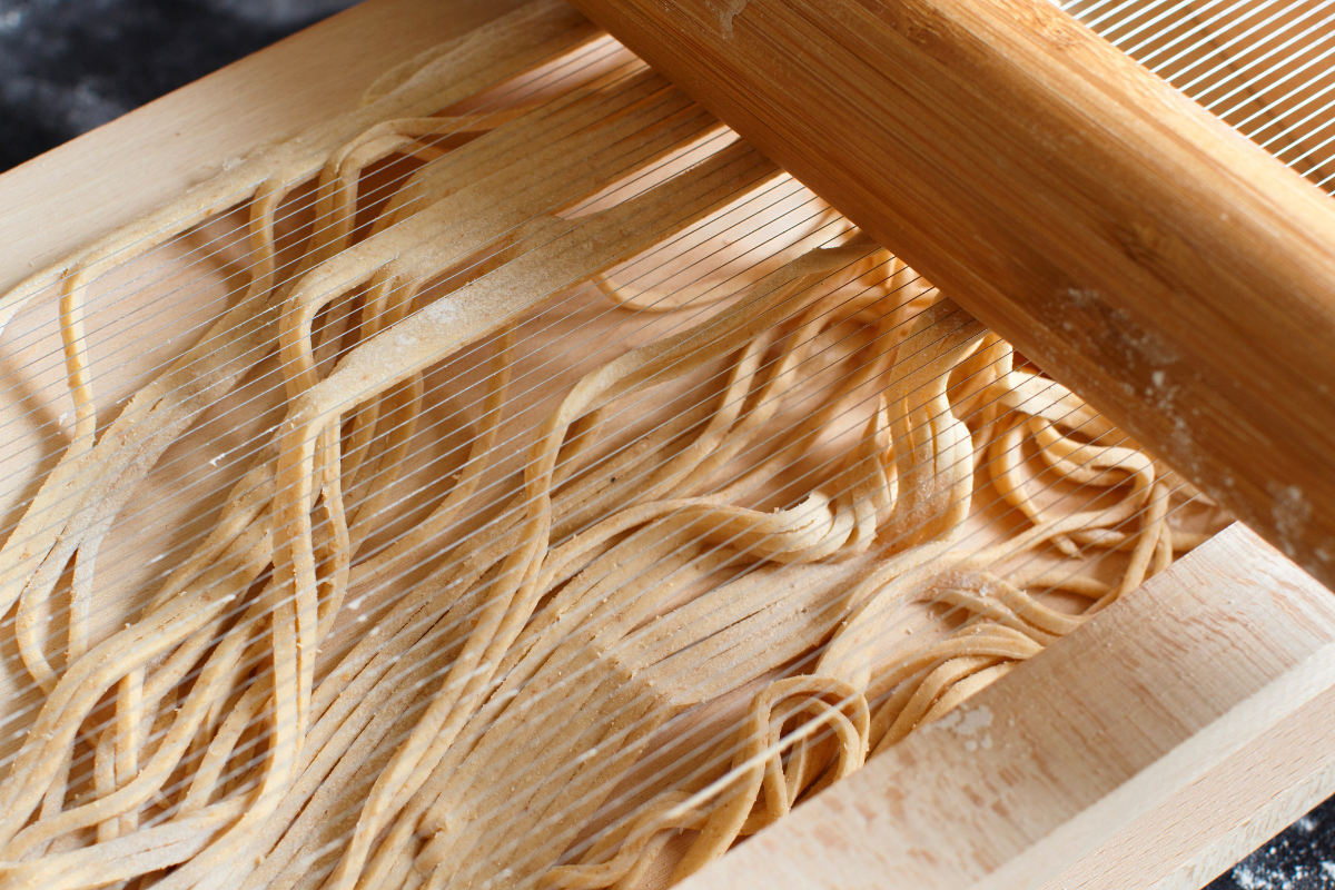 Taglio degli spaghetti alla chitarra con il caratteristico strumento tradizionale